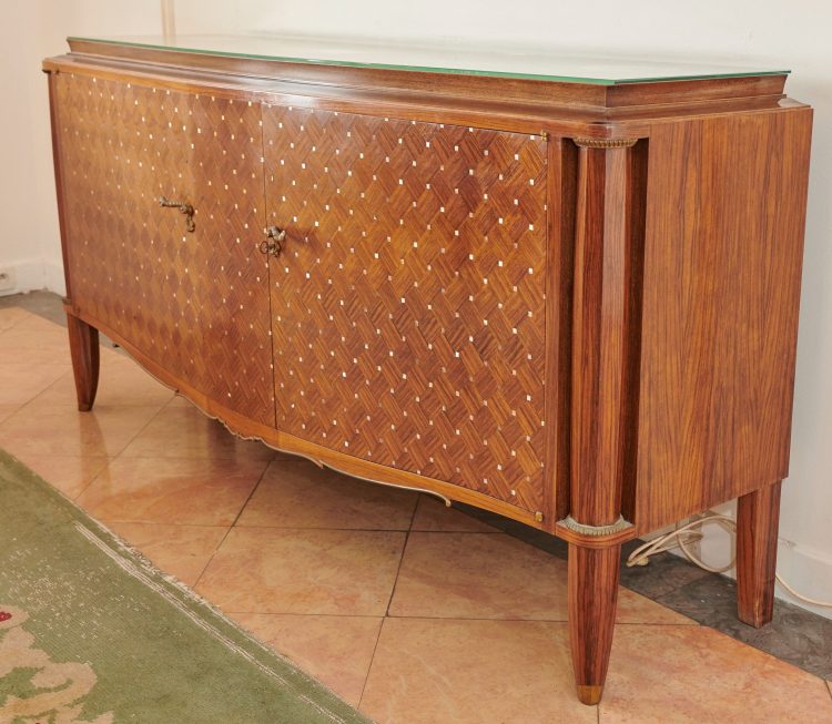 Jules Leleu (1883-1961), commode en noyer incrustée de pastilles carrées en nacre ouvrant à deux portes garnies de poignées torsadées en métal doré et reposant sur des pieds sabres, Hauteur : 96 cm Longueur : 184 cm Profondeur : 52 cm. Estimation : 7000 euros - 8000 euros.