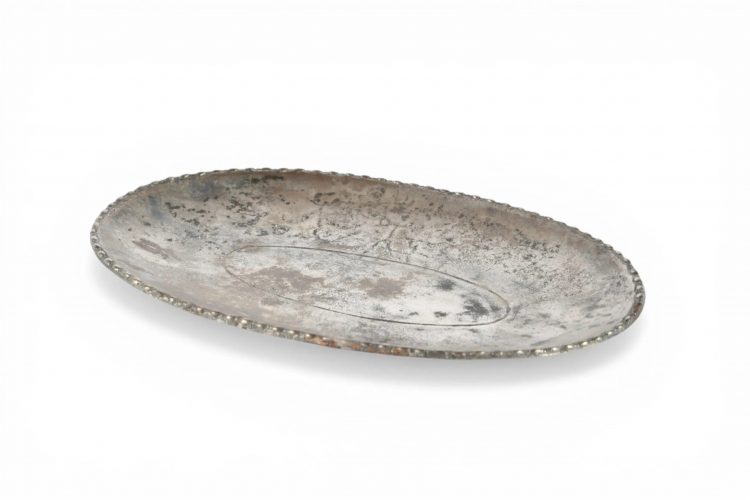 Plateau ovale en argent, légèrement concave, sur pied ovale bas. Sur le rebord, une moulure de perles et de pirouettes. Il n'y a pas d'autre décor qu'un sillon étroit mais net, à l'intérieur, correspondant au tracé du pied. Au revers, un graffite presque effacé : AVC. Milieu du IIIème s. apr. J.-C. L. 19,4 cm. 